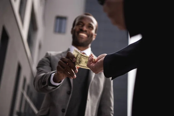 Молодой афро-американский бизнесмен в формальной одежды, принимая деньги на открытом воздухе Стоковая Картинка